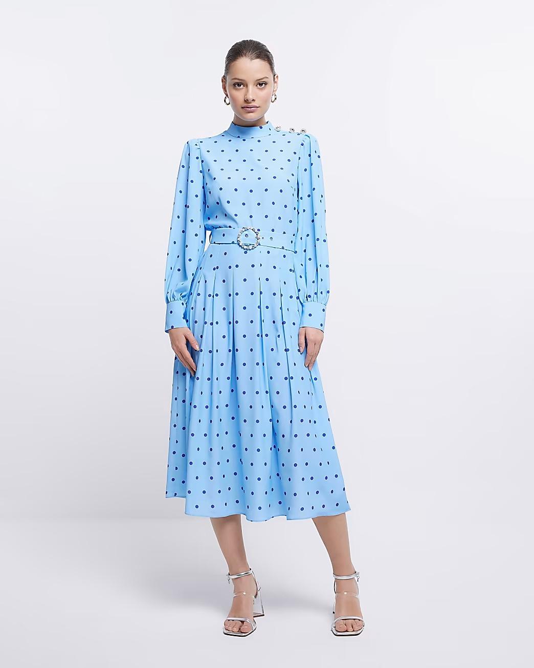 Model wearing a blue polka dot long sleeved dress with a belt