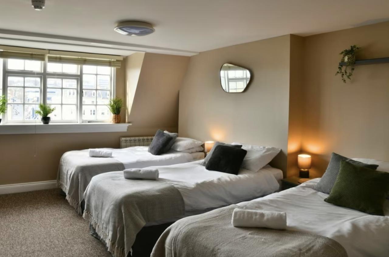 three single beds in a row in a neutral, chic bedroom