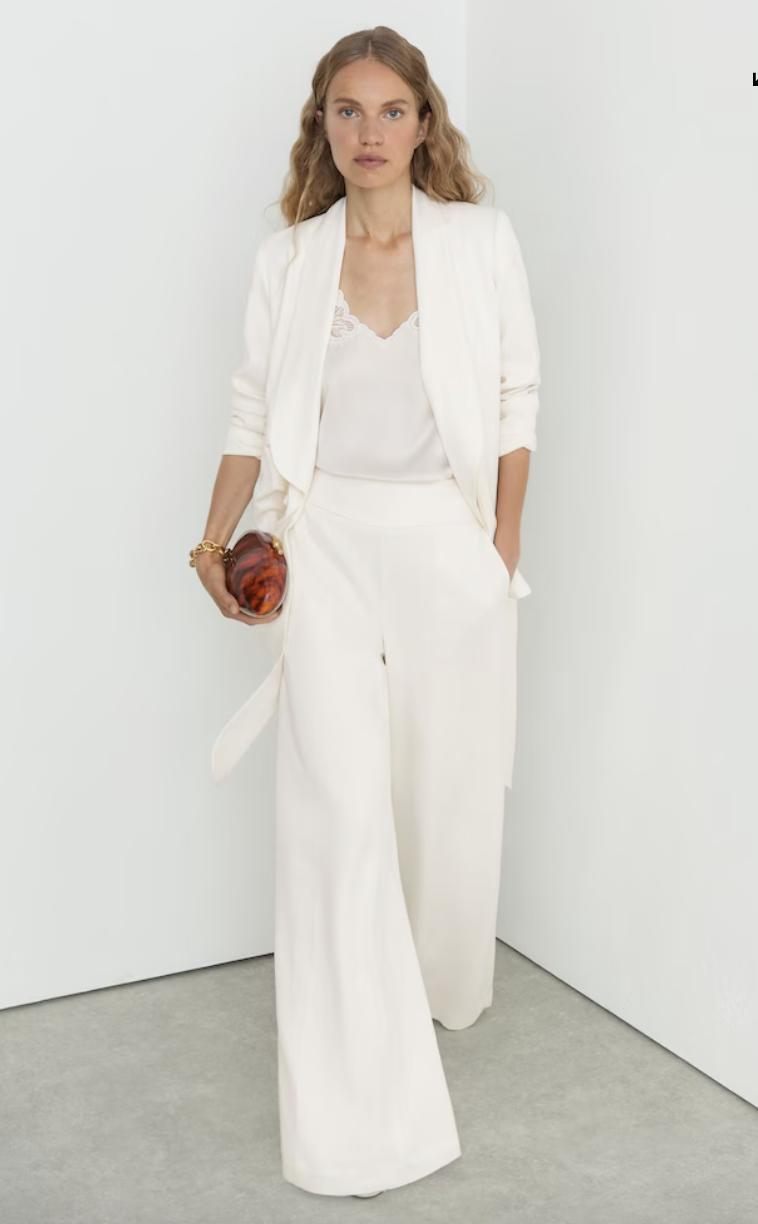 model walking in a flowing white trouser suit with a wrap blazer