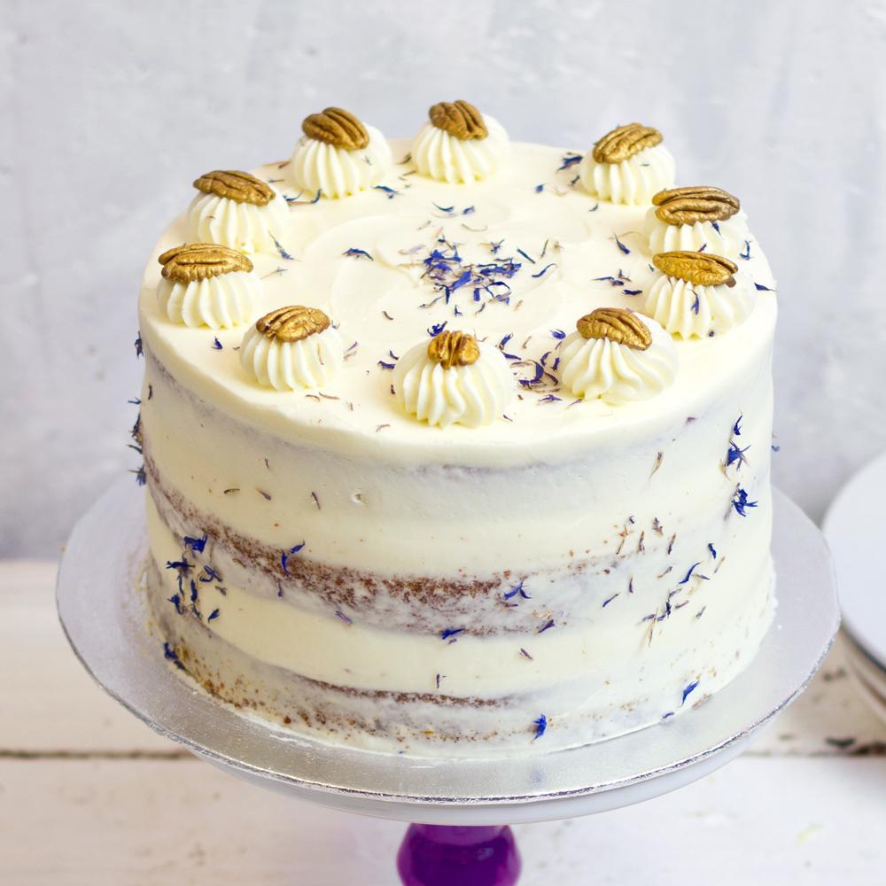 semi naked carrot cake with lilac decoration and gold sprayed pecan toppings