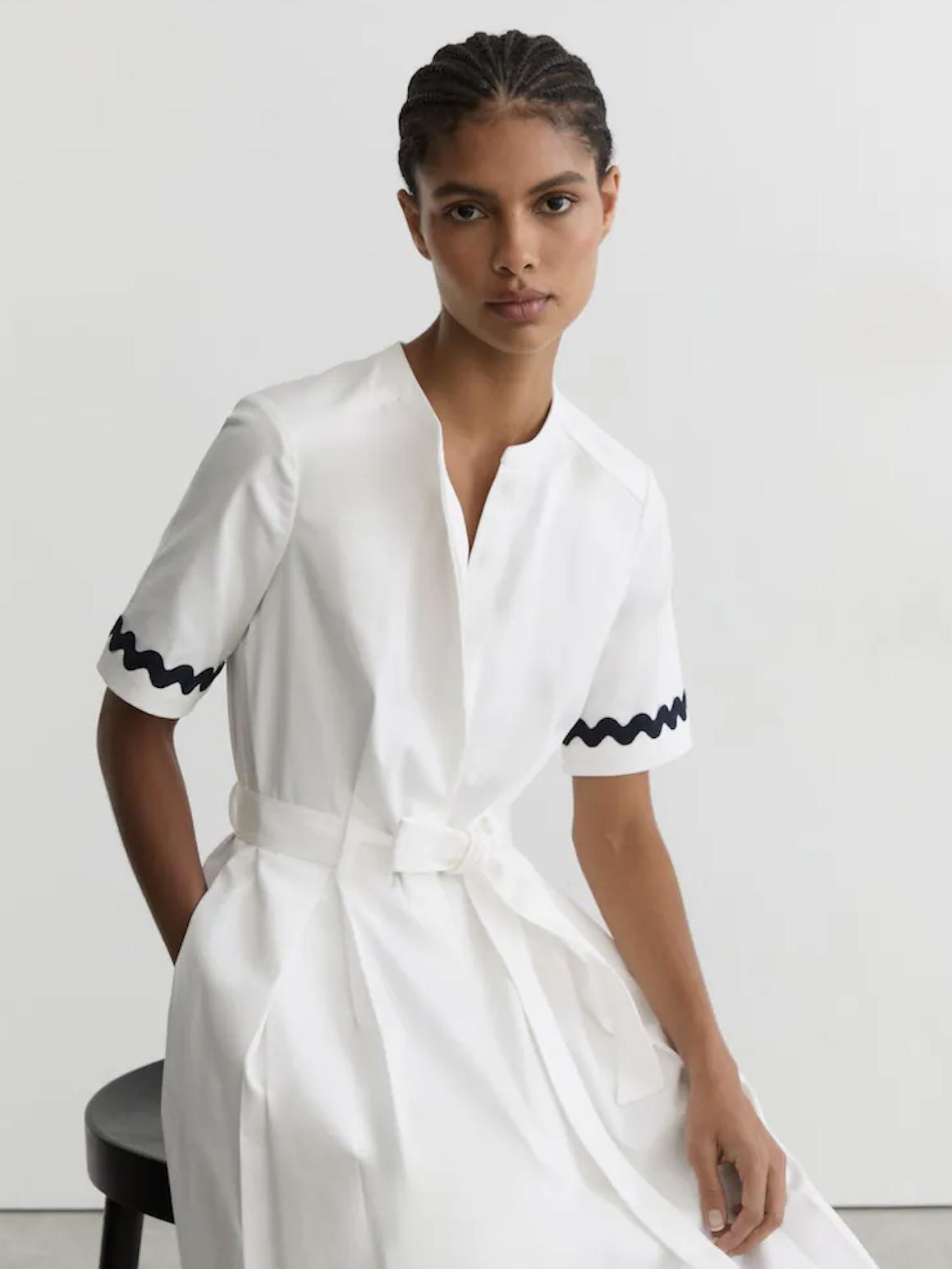 model wearing a tailored white cotton wave edged dress from Reiss