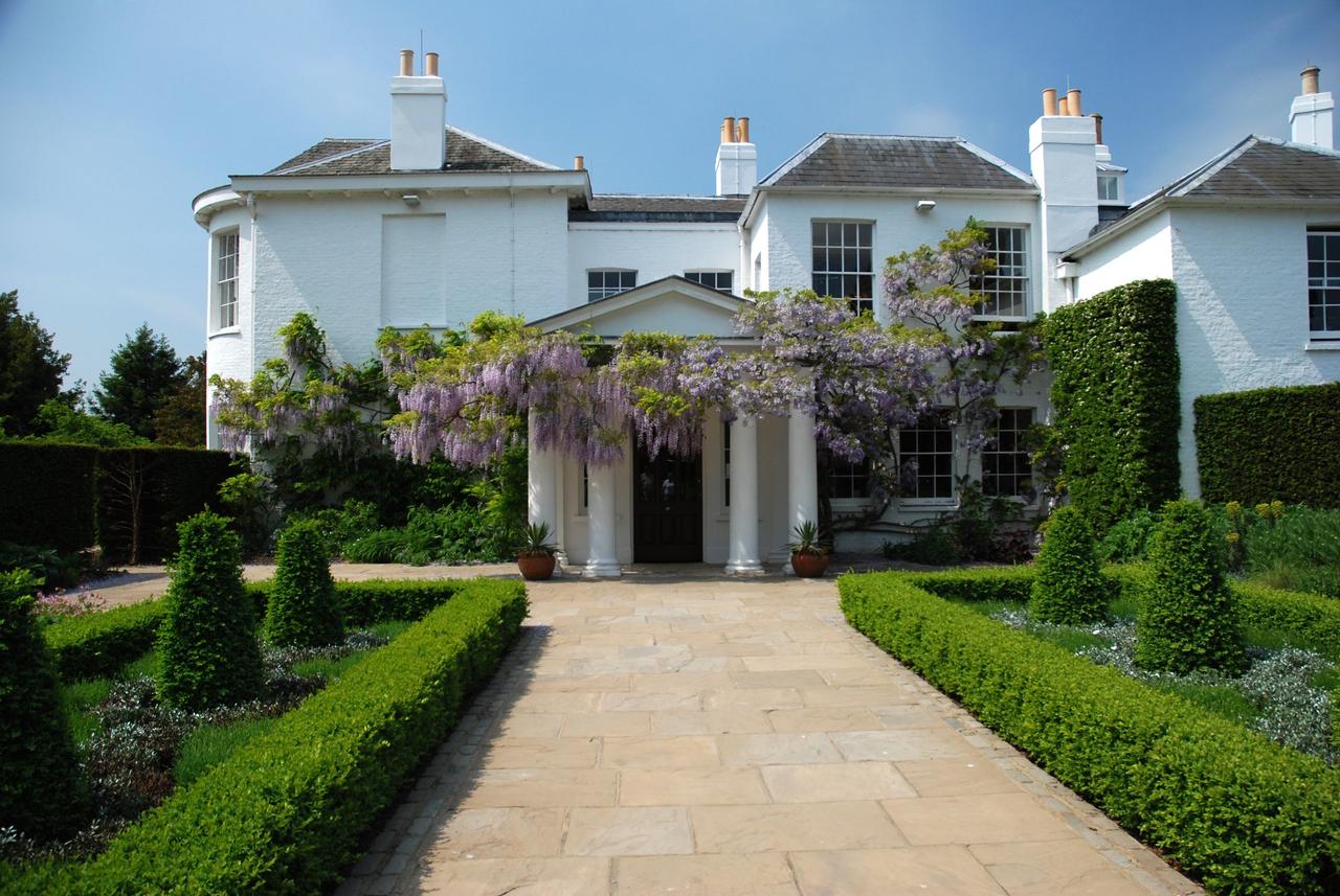 Exterior view of stately home wedding venue Pembroke Lodge, showing purple wisteria growing across the white walls