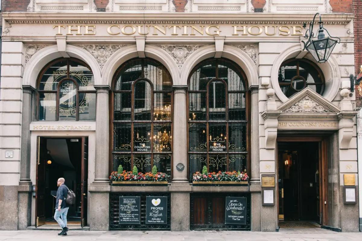  the outside of the counting house pub in london with someone walking past its doors