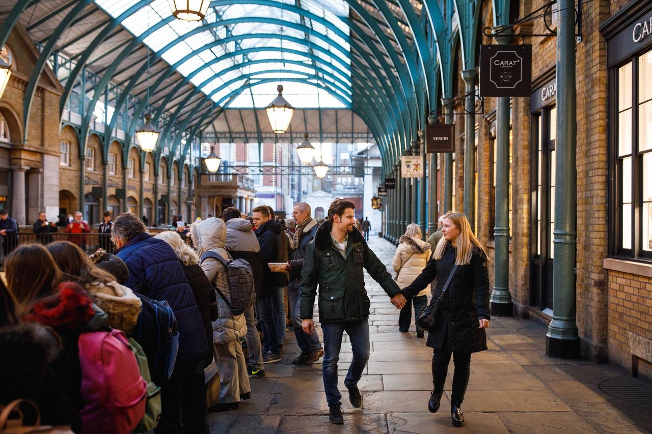 Couple walk hand in hand through Covent Garden market