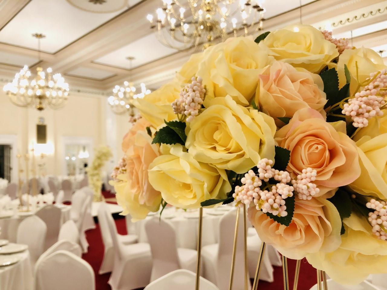 a close up of yellow flowers with wedding tables behind we
