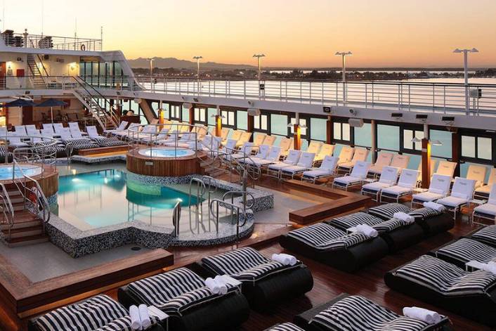 The gorgeous pool and jacuzzi deck on one of the ROI cruise ships which sails the French Polynesia cruise journey complete with sunbeds and an ocean sunset view