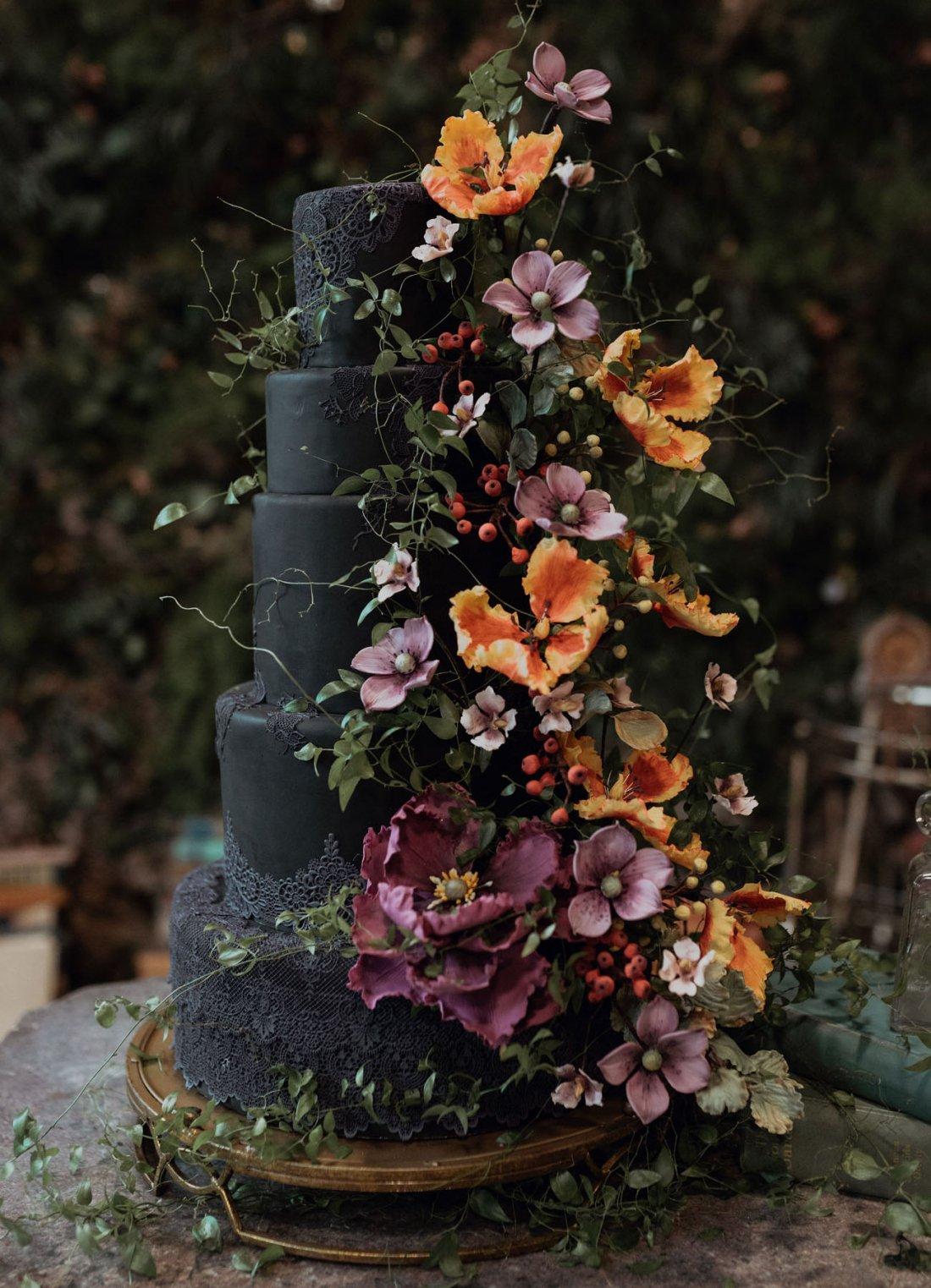 Five tiered black rustic wedding cake with orange flowers