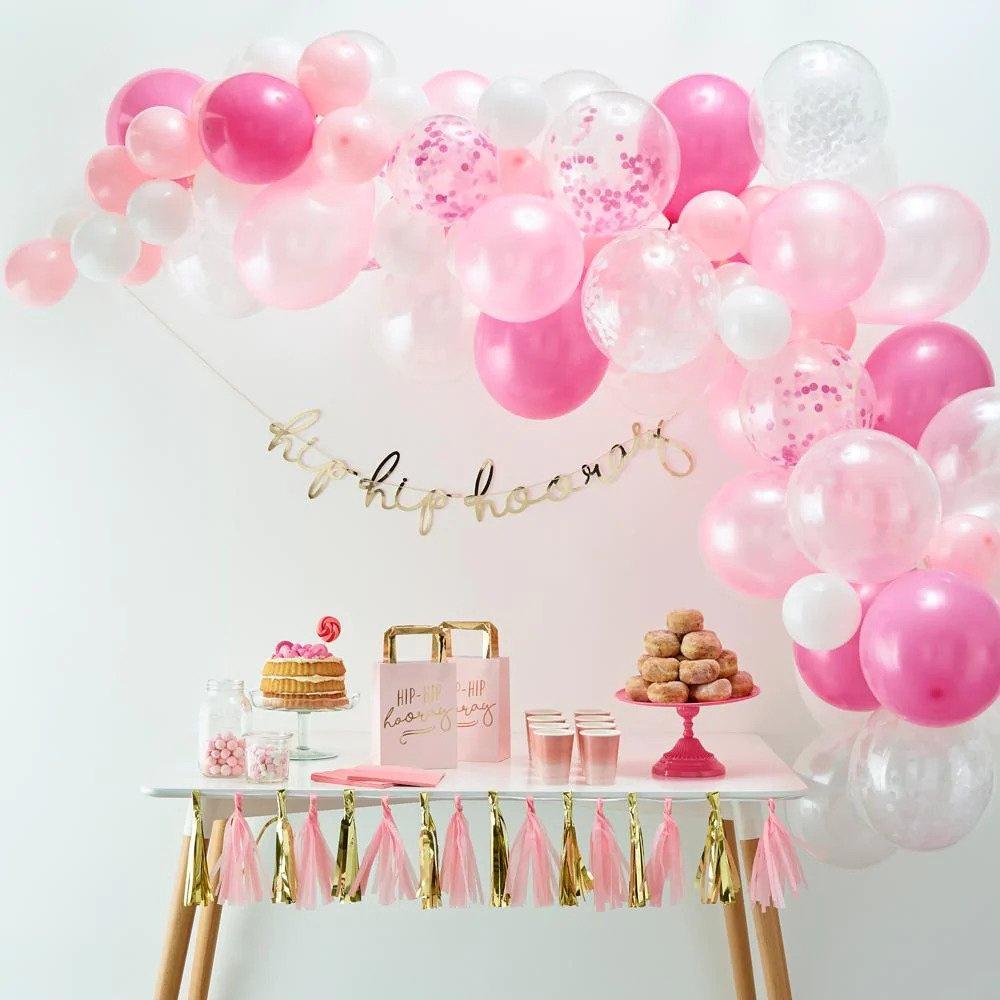 A pink balloon arch on top of a dessert table