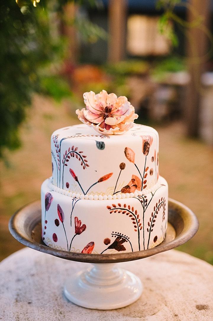 Two tiered white fondant rustic wedding cake with hand painted flowers