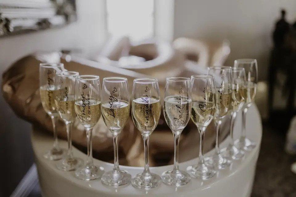 A bar with a line up of personalised champagne glasses for the bride and bridesmaids, all full of champagne