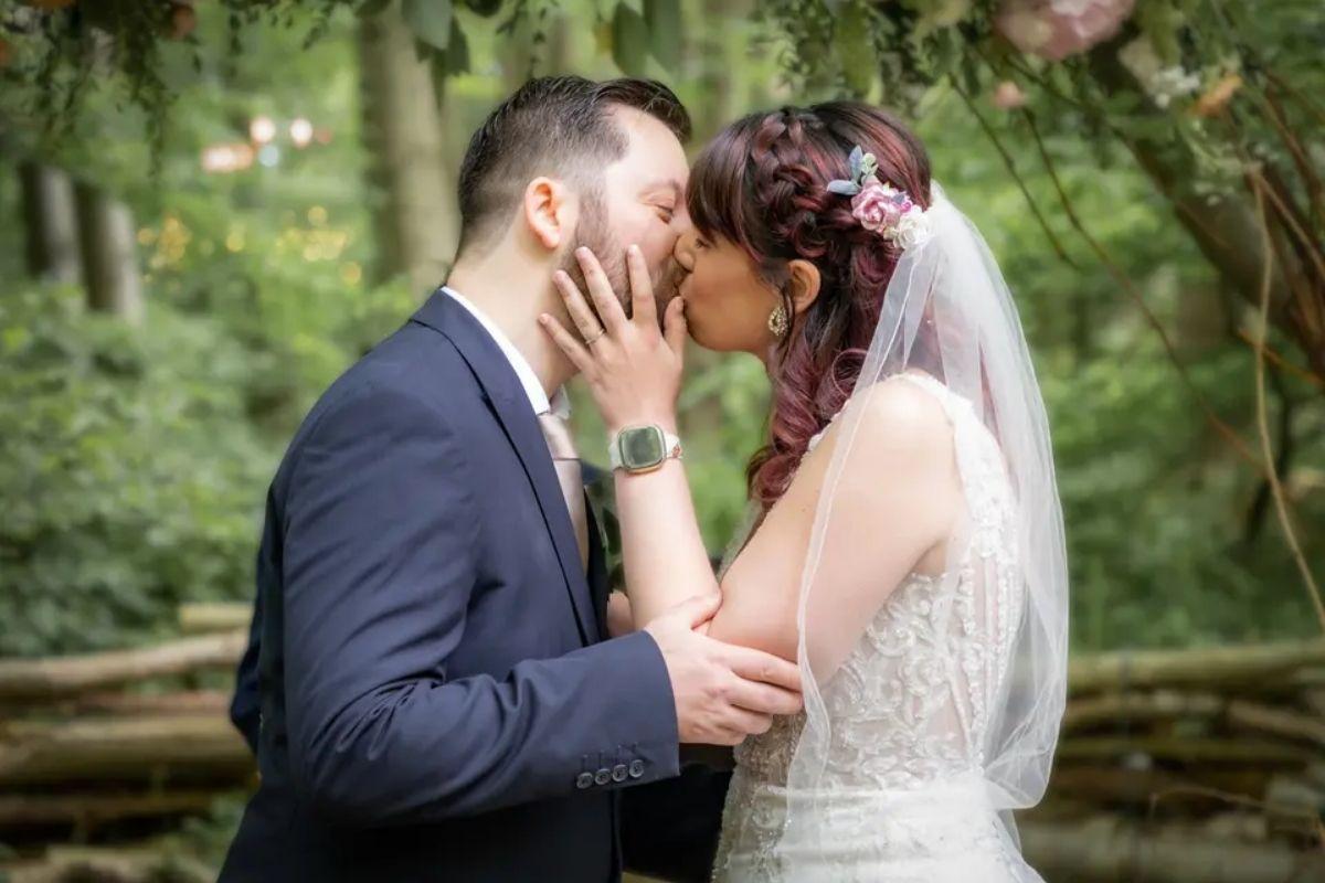 a bride with braided red hair kissing her groom in a wedding suit
