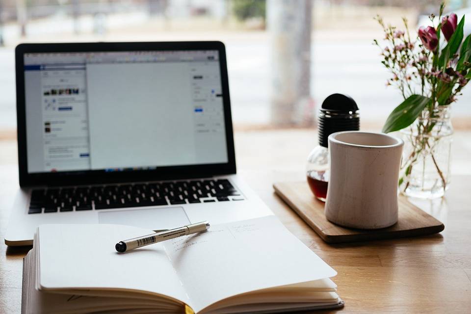 Open laptop with notebook and pen in front on a desk