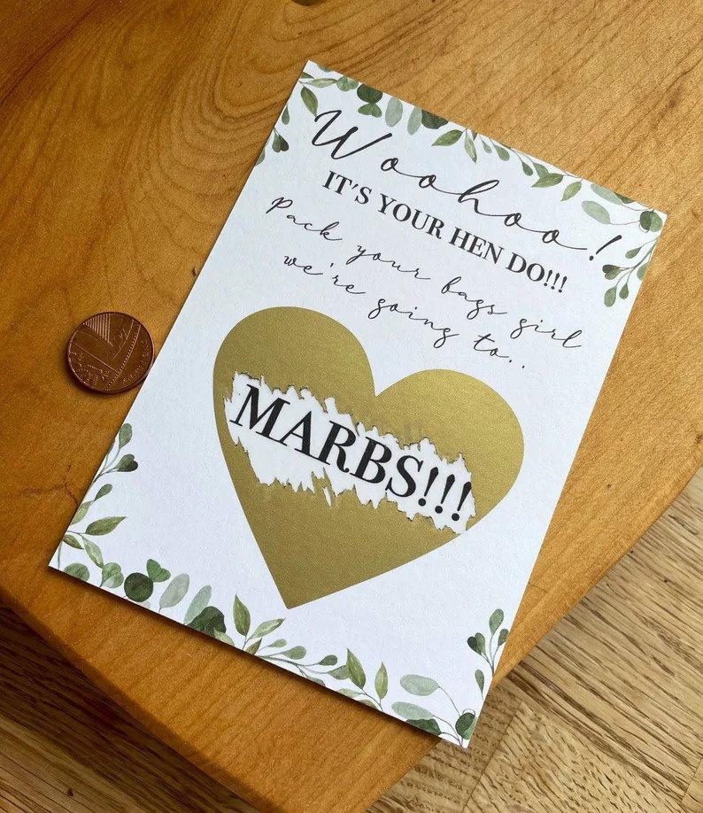 Scratch hen do invitation where the destination of 'Marbs' is revealed when gold foil is scratched off