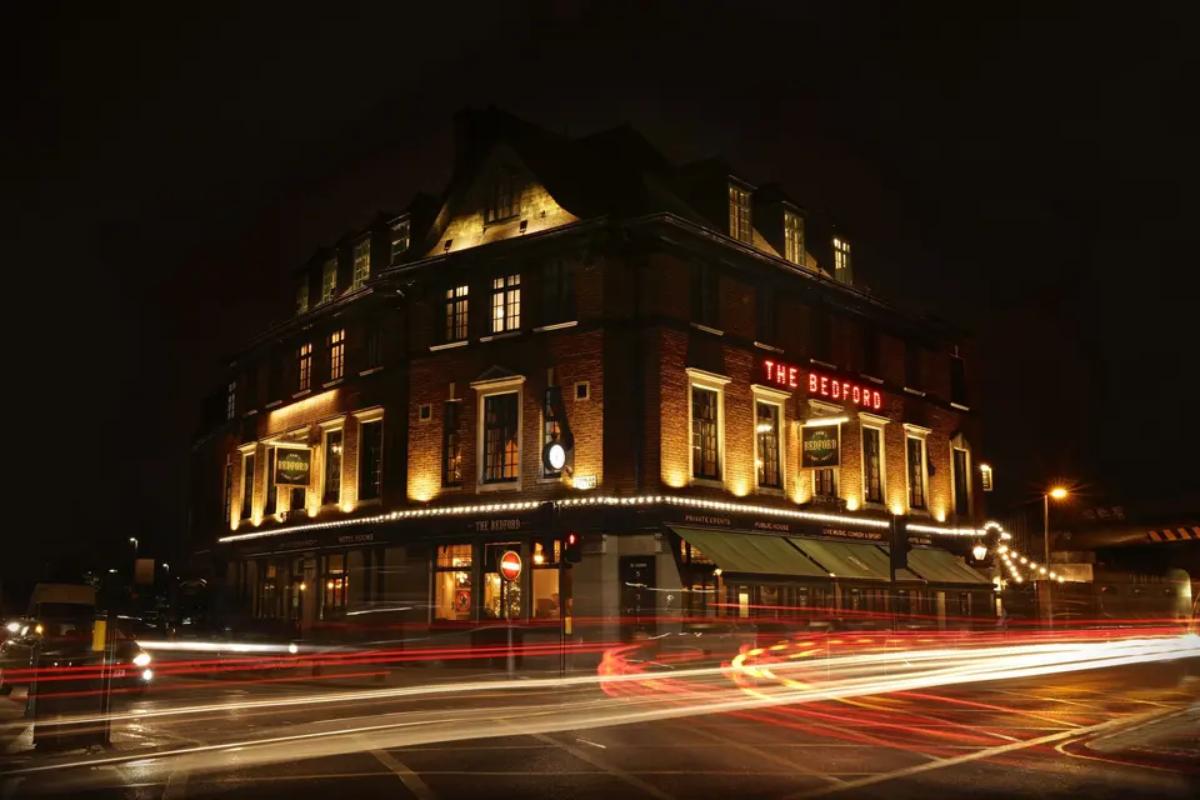  an outside shot of the bedford pub in balham at night with lights smeared across the front