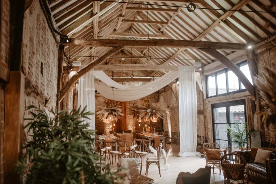 A stone brick barn in Suffolk decorated with pampas grass, beige drapes and fairy lights