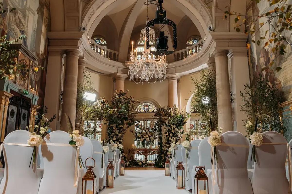  a grand wedding ceremony set up in a small london wedding venue with a dome ceiling and pillars by the walls