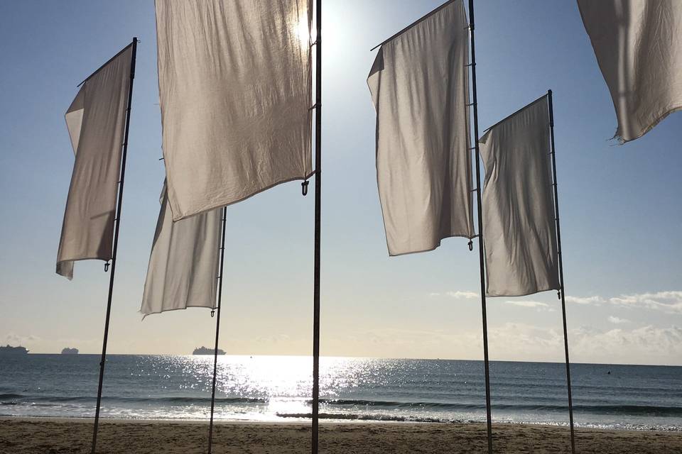 Beige flags on poles blowing in the wind, set against a blue sky