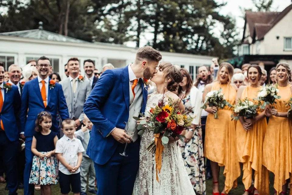 Bride and groom kiss in front of their guests and venue