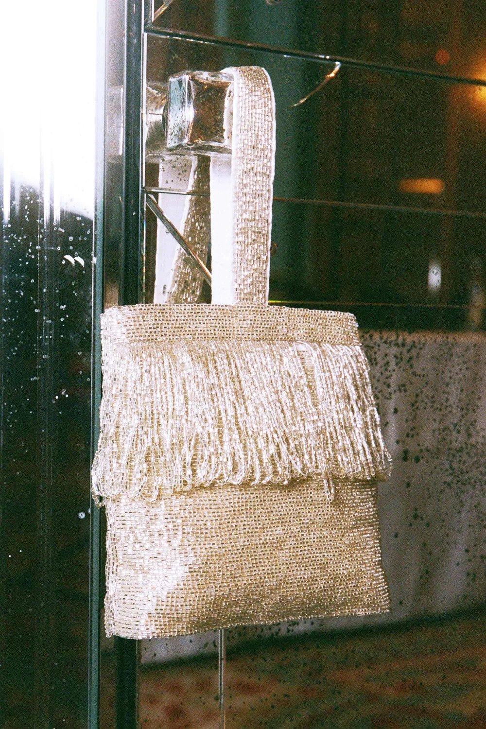 A silver beaded party style bag handing on a rack