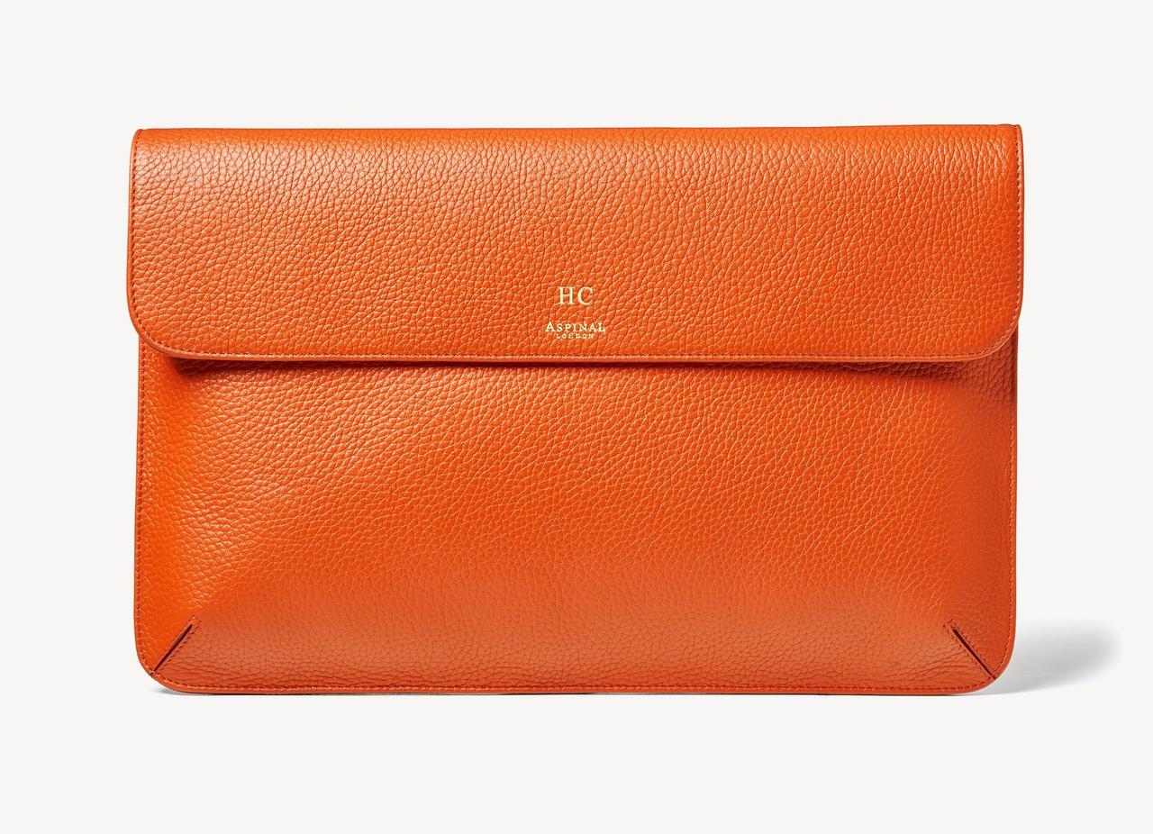 Image of a leather laptop case in burnt orange with gold-foil monogram