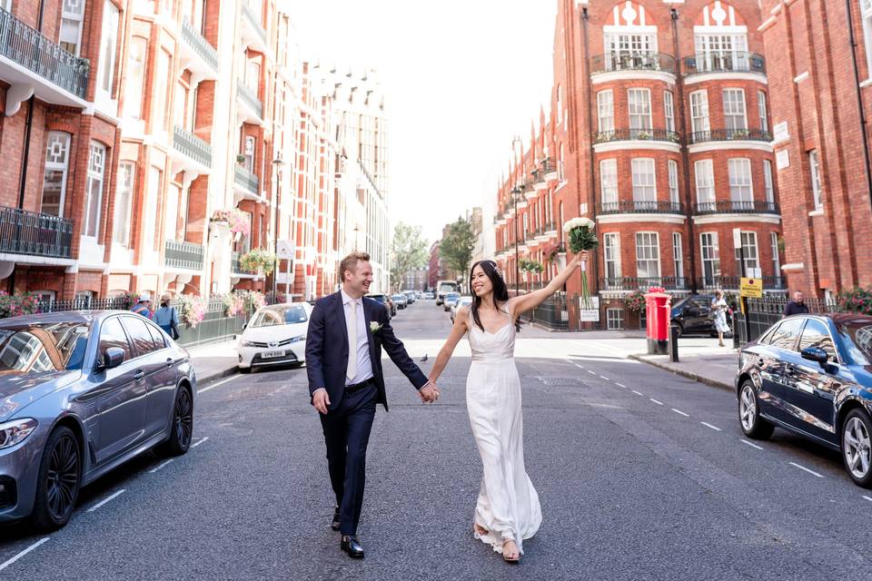 Newly married bride and groom holding hands on a near-empty London street