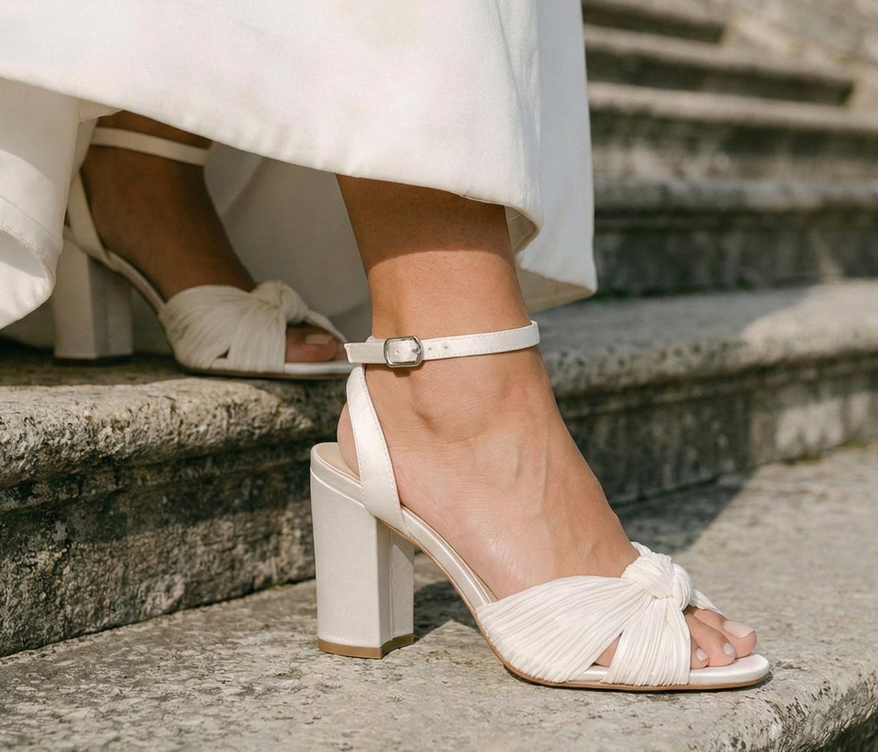 A close-up of a bride's peep-toe sandals as she walks down some steps.