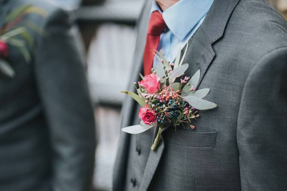 Men's grey suit with red tie and floral buttonhole