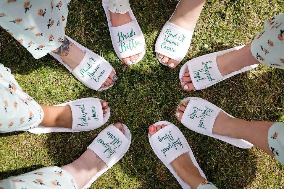 A photo of eight feet in personalised sliders all pointing in together in a circle. The sliders say things like Bride Billie and Maid of Honour Carrie