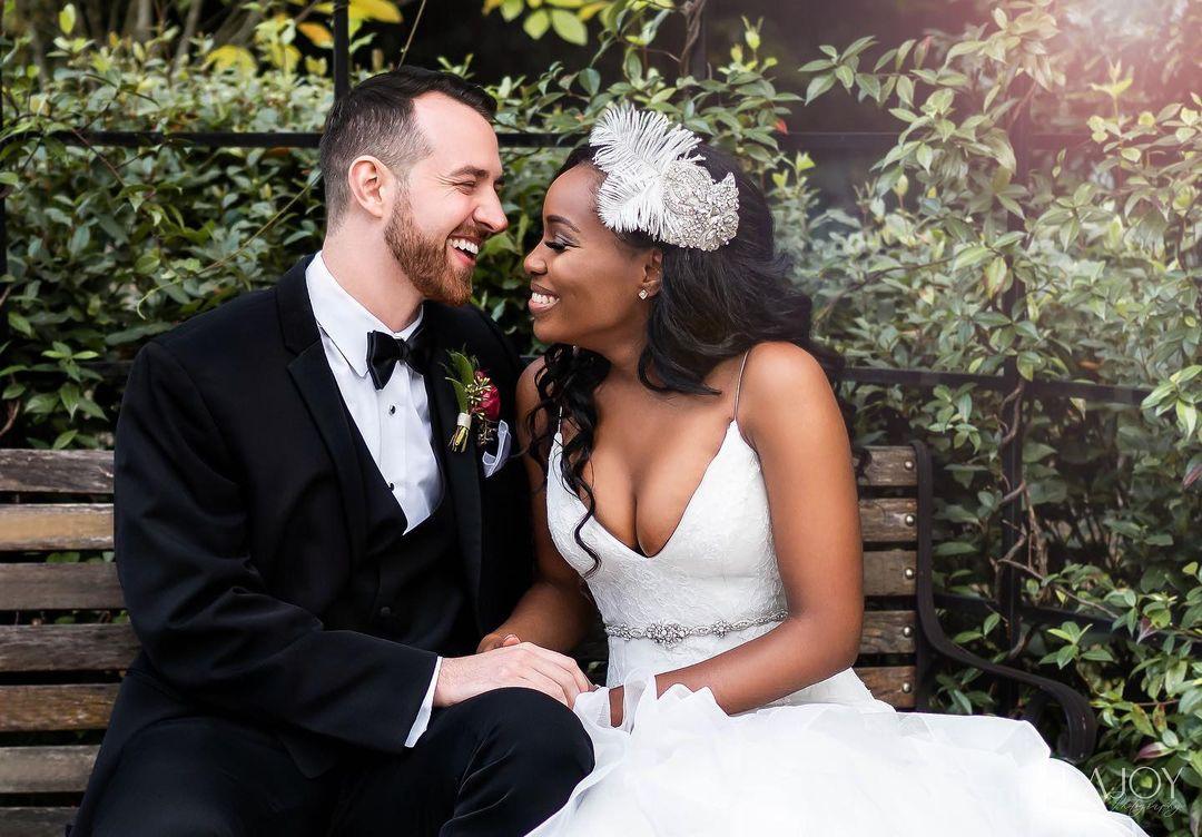 lauren and cameron smile at their wedding whilst sitting on a bench outdoors