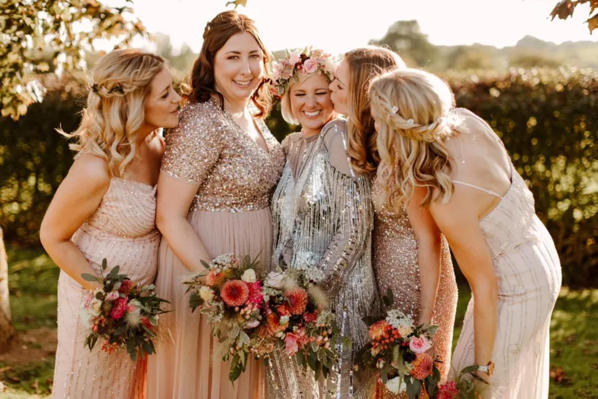 a unique bride wearing a silver sequin wedding dress with her bridesmaids wearing neutral mix and match bridesmaid dresses all holding bouquets 
