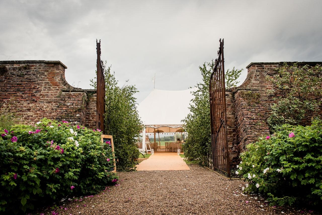 A walled garden wedding venue opening out on to a tepee-style stretch tent.