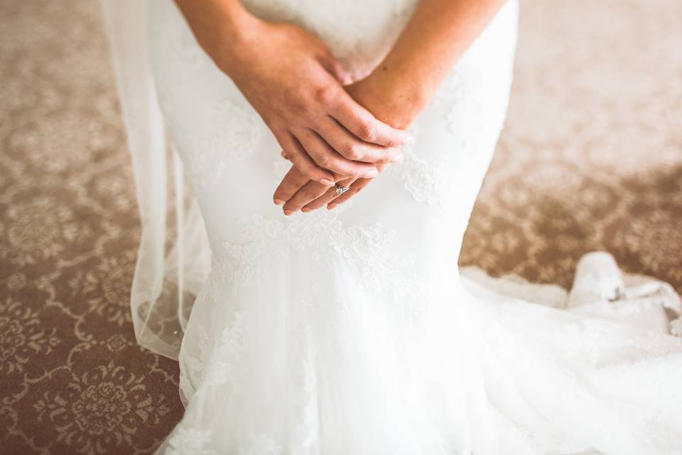 Brides hands clasped against white dress
