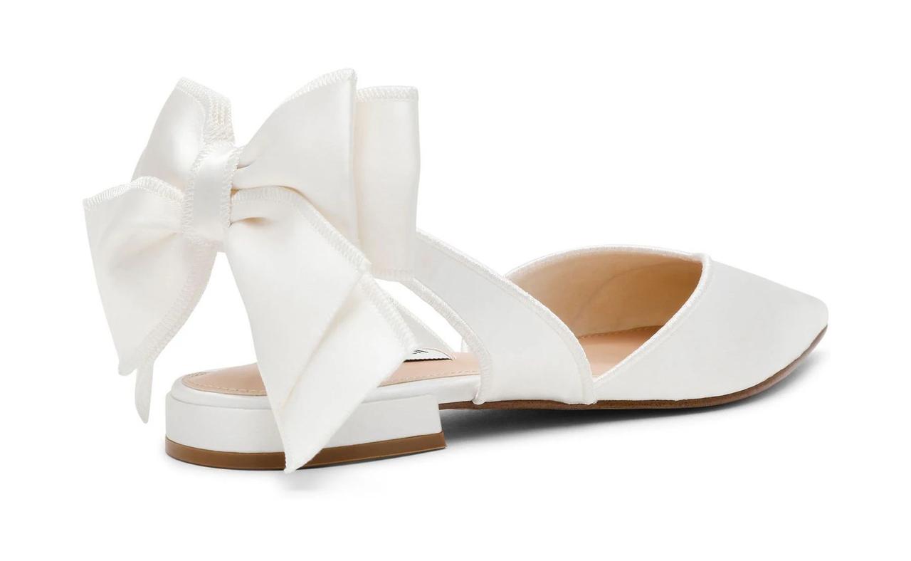 A white satin pointed slingback shoe with bow detail at the back. 