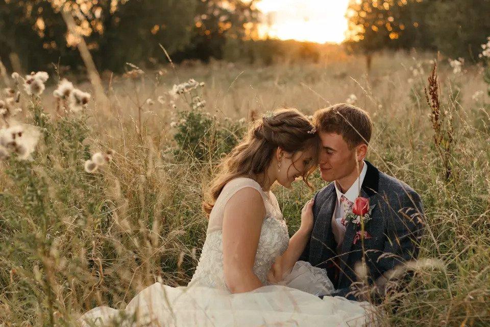 Bride and groom embrace in a grain field at golden hour