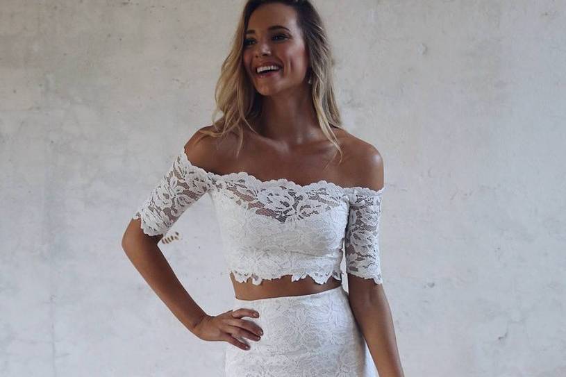 Model wearing a lace crop top and skirt two-piece wedding dress