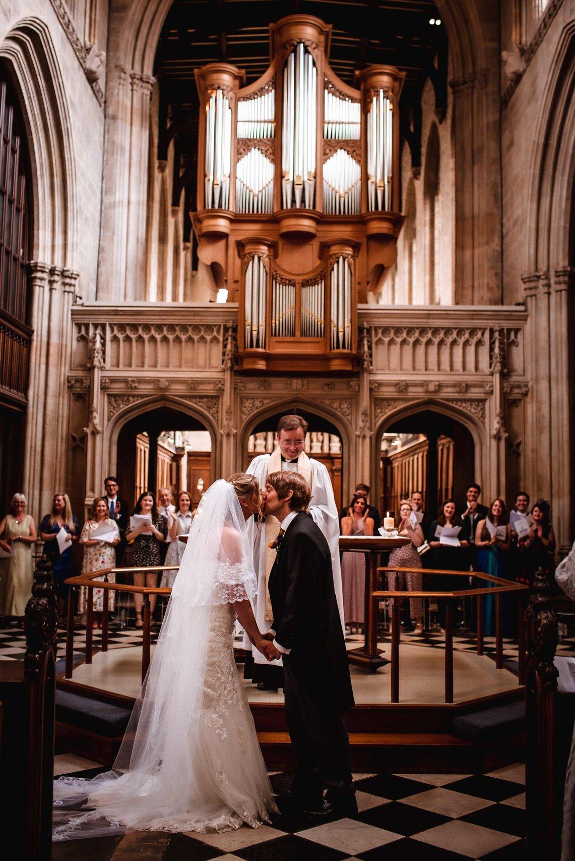 A bride and groom kiss at the altar 