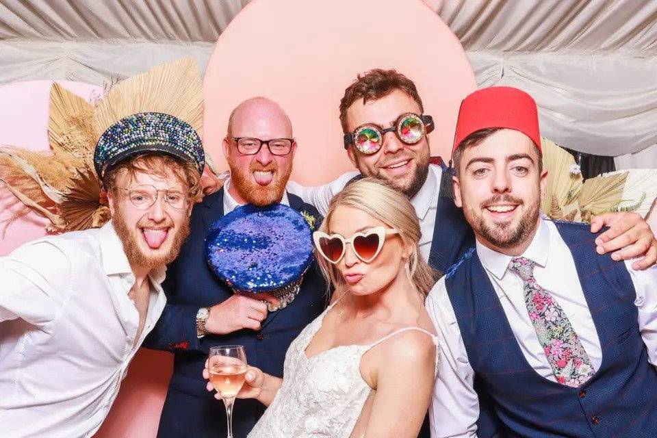 Bride, groom and friends posing in a photo booth with props