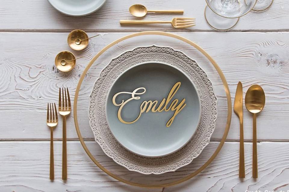 Wooden name tag on a blue plate with gold cutlery 