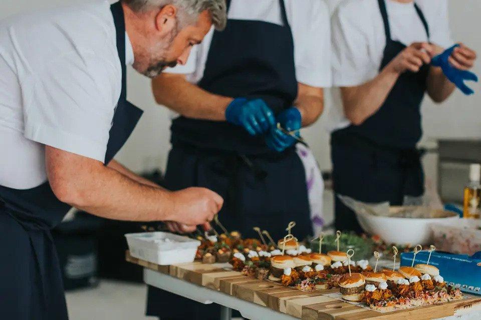 A chef prepares several trays of canapes
