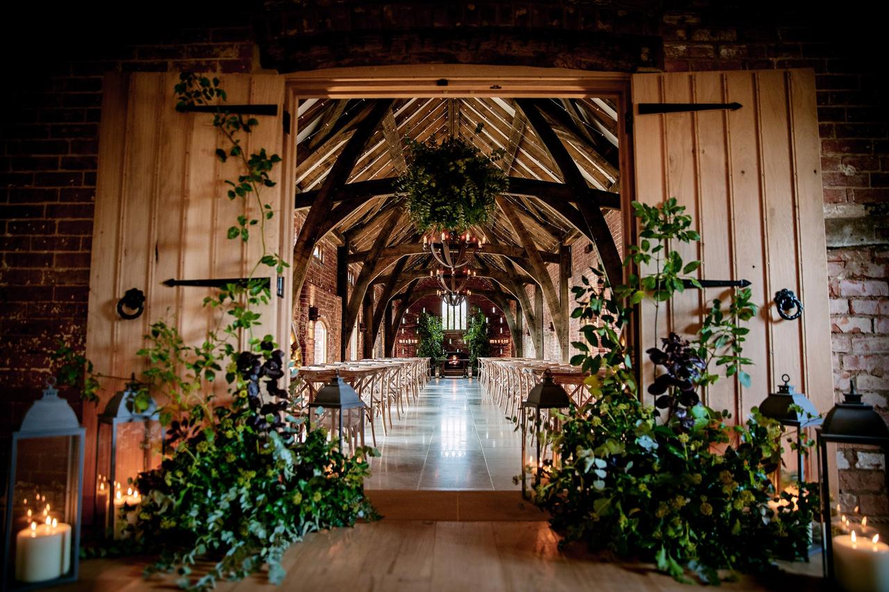 Foliage decorated barn door entrance to a wedding ceremony
