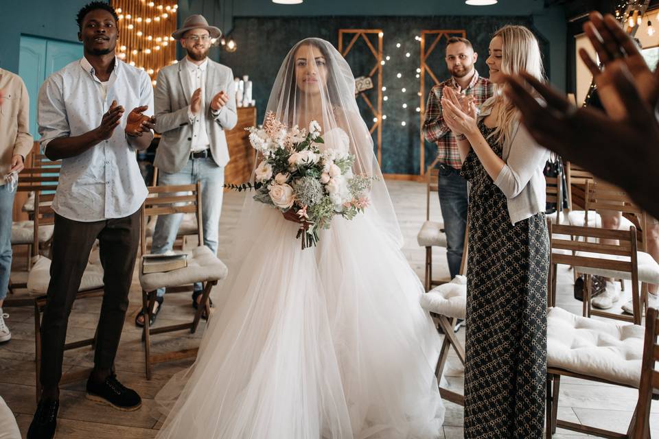 Bride walking down the aisle as guest stand up and applaud