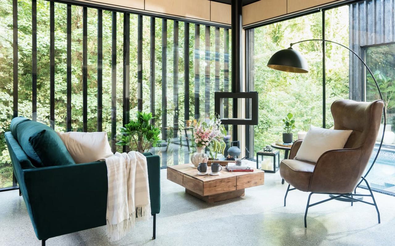 Interior shot of a woodland cabin rental with seating and views of the forest 