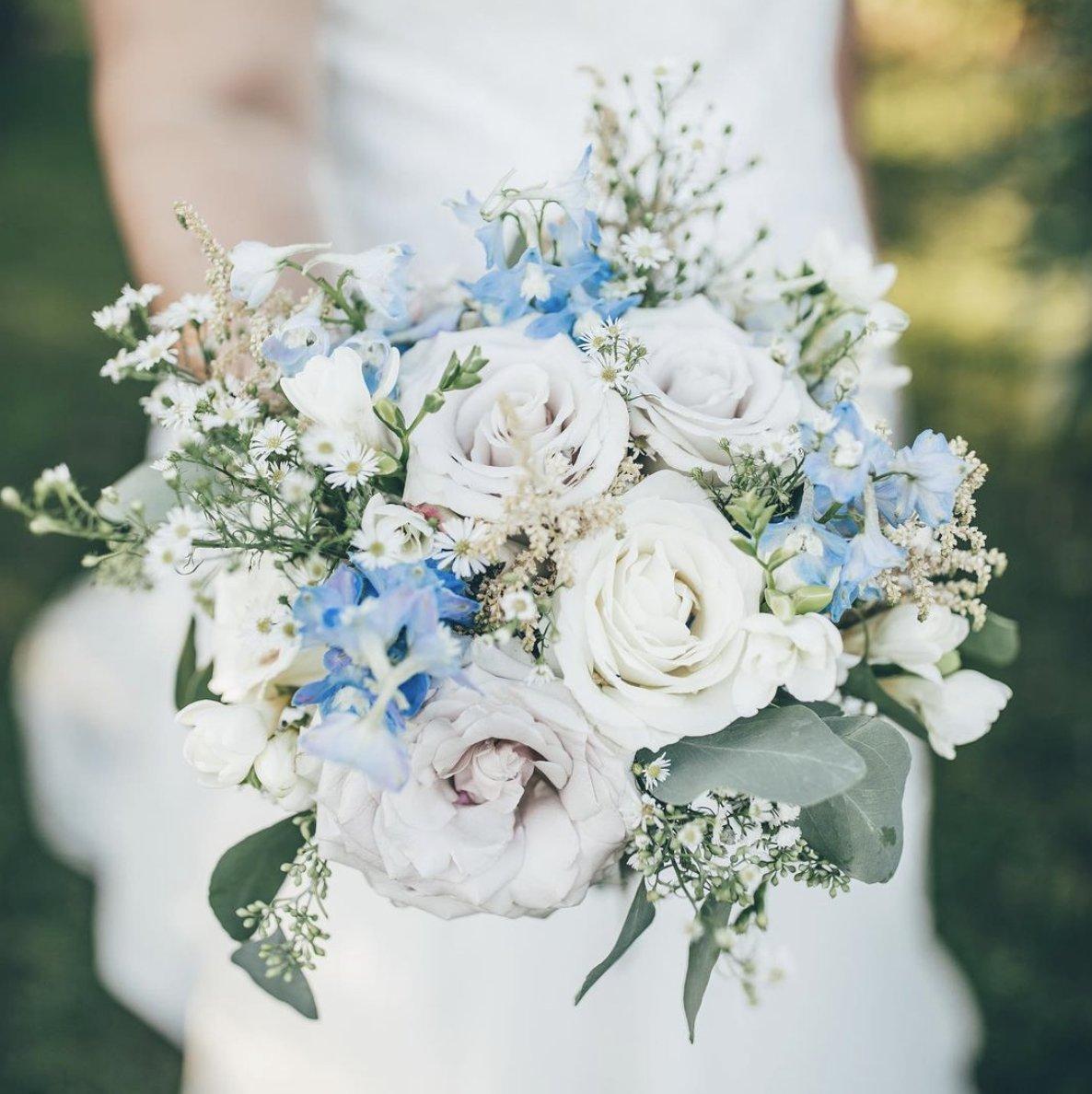 White bride in a white dress holding a blue and white bouquet in the foreground