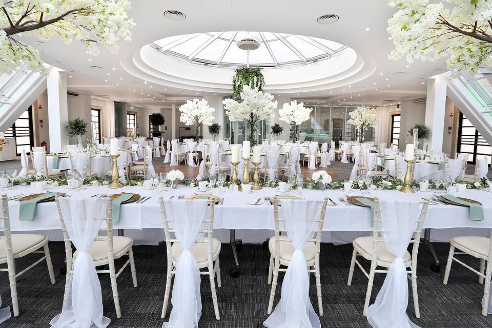 A lavish wedding breakfast set in a room with sweeping views of the green surroundings