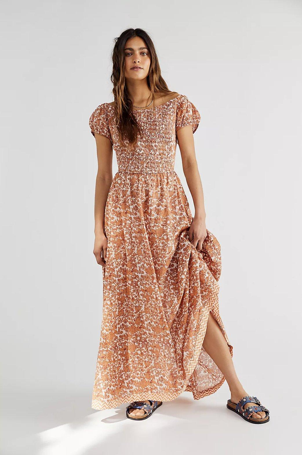 Image of a model wearing an orange floral maxi dress with slightly poofed sleeves
