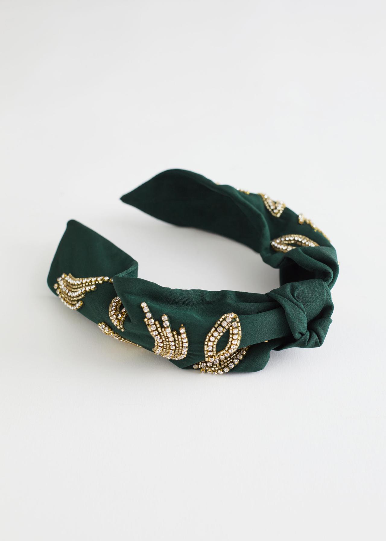 A green headband with gold and crystal embellishment