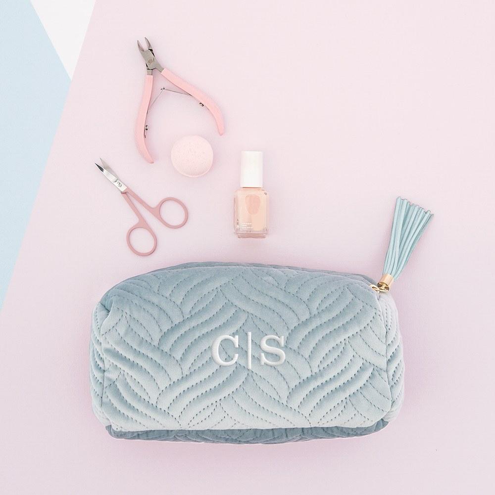 Blue makeup bag with nail polish, scissors and tweezers spilling out