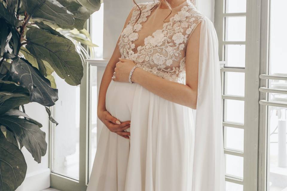 Pregnant bride cradling her bump in a flowing white gown