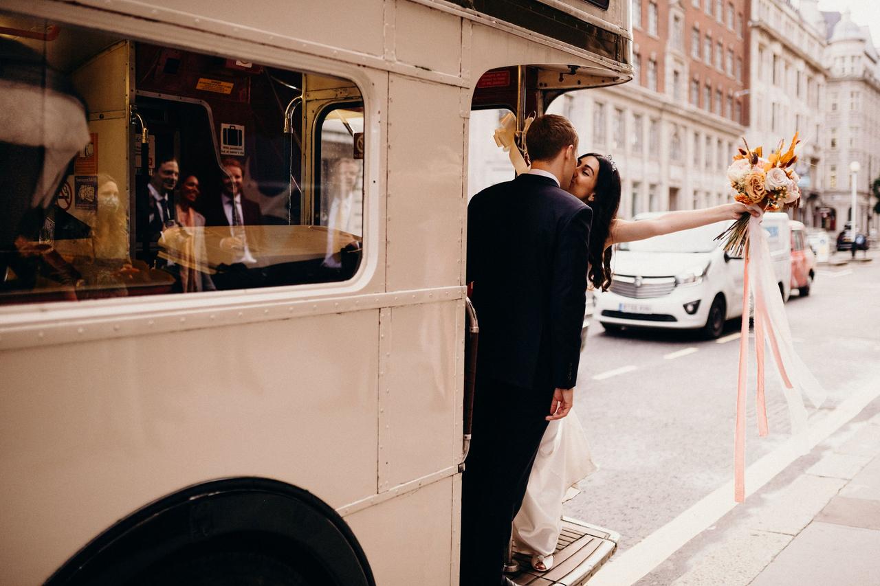 Bride and groom hanging out of a bus