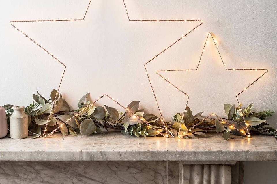 two metal stars with fairy lights adorning them